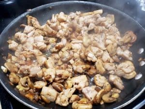 chicken onions and mushrooms cooking in a frying pan