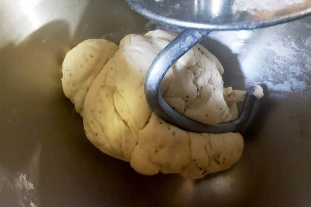 bread dough in stand mixer with dough hook in metal bowl