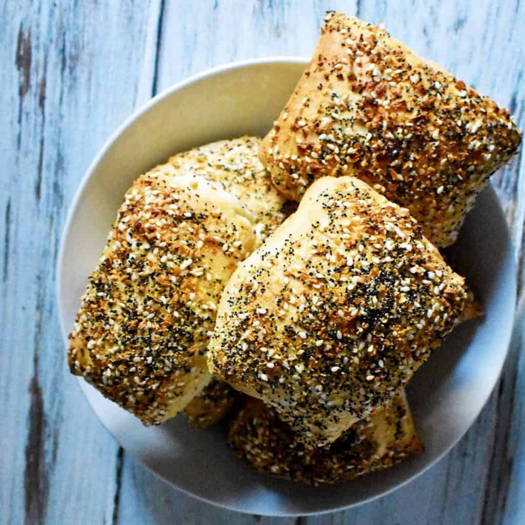 everything dinner rolls in white bowl on white wooden table