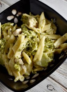 Chicken Alfredo in a black bowl on a white wooden table