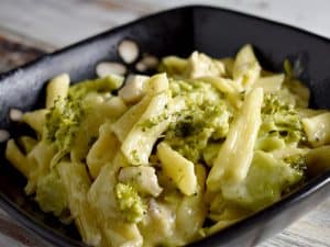 Chicken Alfredo with broccoli in a black bowl on a white wooden table