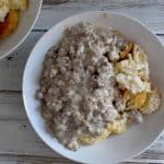 overhead photo of biscuits and gravy in a white bowl on a white wooden table