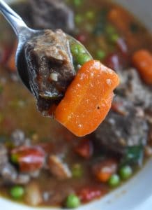 Insant Pot beef stew with beef and carrot on a spoon above a bowl
