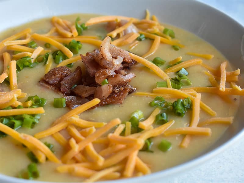 instant pot loaded baked potato soup with cheese and bacon in a white bowl