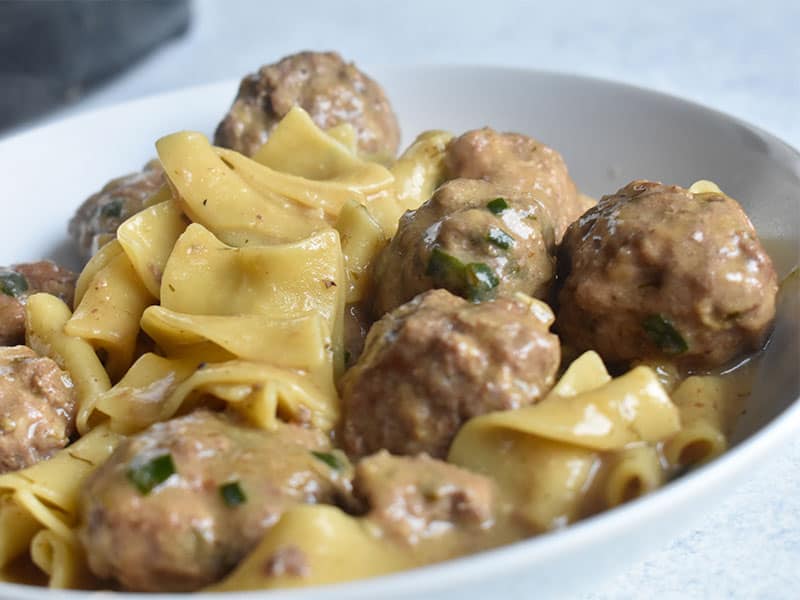 instant pot swedish meatballs in a white bowl with egg noodles