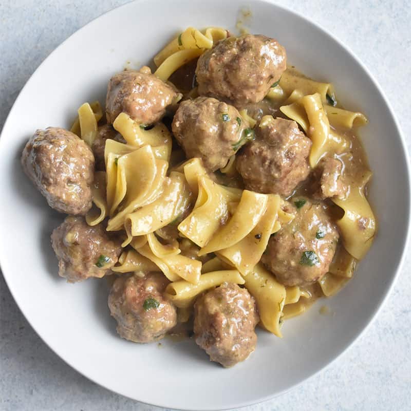 overhead shot of swedish meatballs in a white bowl on a white table