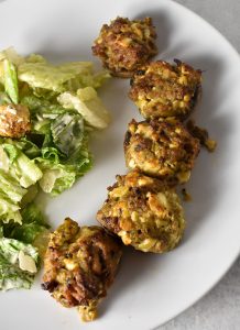 Sausage Stuffed Mushrooms on a white plate with ceasar salad