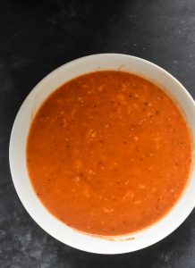 instant pot red pepper soup in a white bowl on a gray table