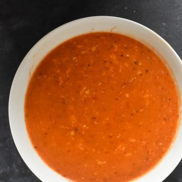 instant pot red pepper soup in a white bowl on a gray table
