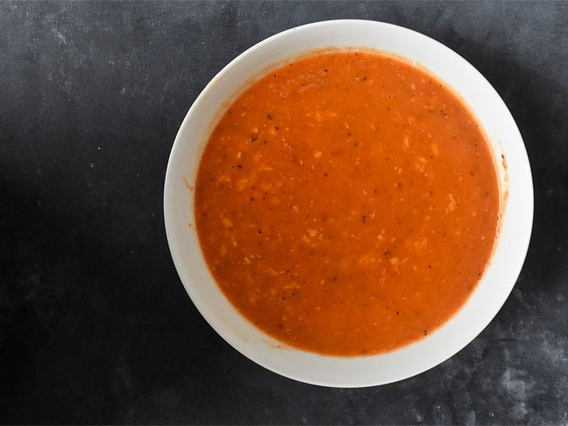 instant pot red pepper soup offcentered in a white bowl on a gray tabletop