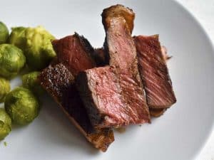 sous vide steak on white plate with brussels sprouts