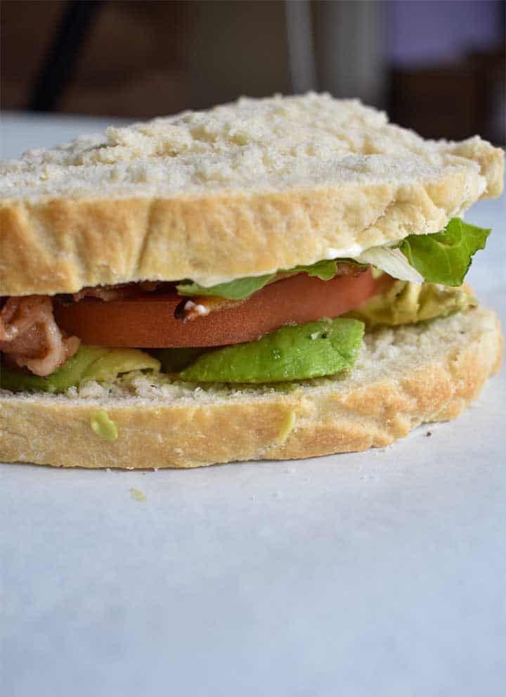 BLT Sandwich made with sous vide bacon on white bread with avocado on a white table