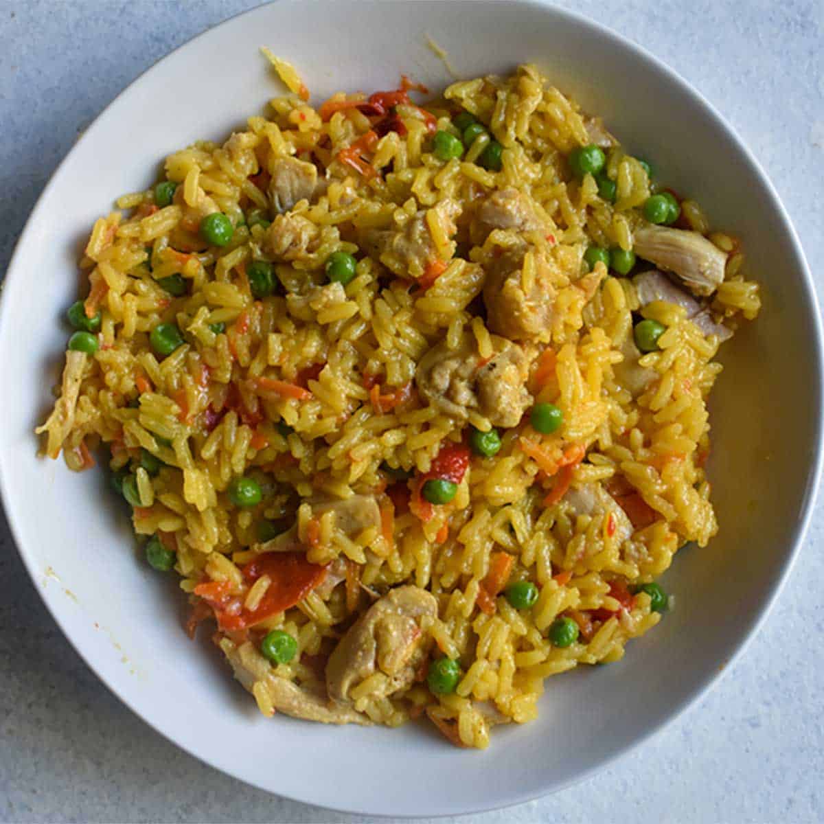 instant pot chicken and yellow rice in a large white bowl on a white table