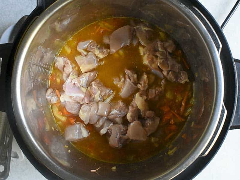 chopped chicken thighs sitting on top of a rice, veggie and chicken broth mix in an instant pot