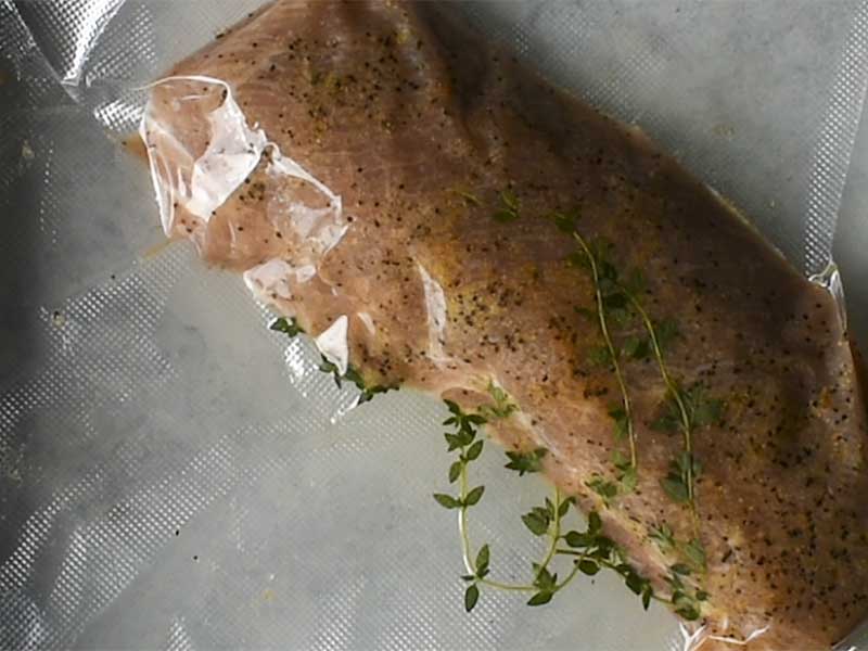 pork tenderloin sealed in a sous vide bag with fresh thyme