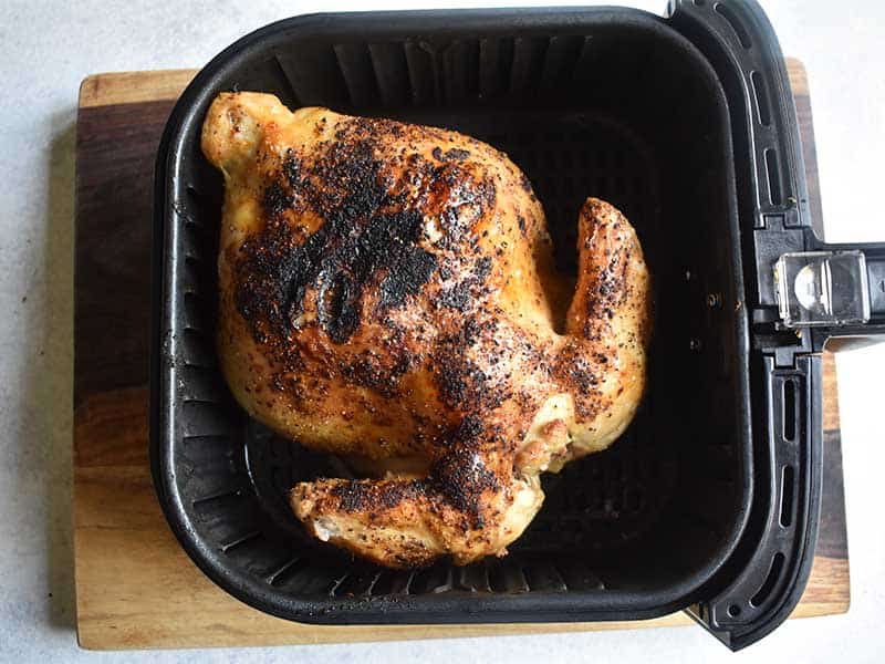 cooked whole chicken in an air fryer basket 