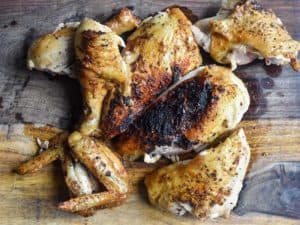air fryer whole roasted chicken that has been carved into sections and placed on a wooden cutting board