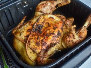 roasted whole chicken in a black air fryer basket