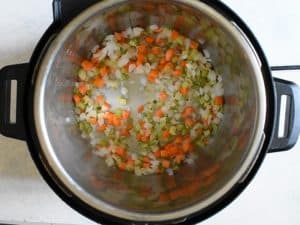 overhead shot of celery, carrots and onion being sauteed in an instant pot