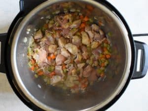 Overhead shot of chicken, celery, carrots and onion being sauteed in an instant pot for chicken and dumplings.