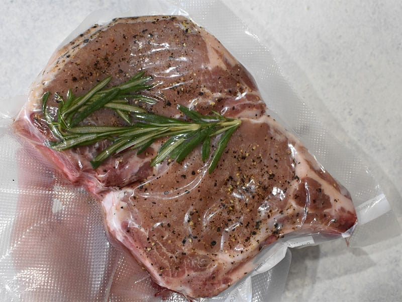 pork chop with rosemary inside of a vacuum sealer bag