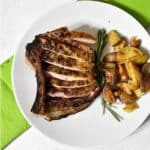 overhead shot of a sous vide pork chop sitting on a white plate with a green napkin underneath