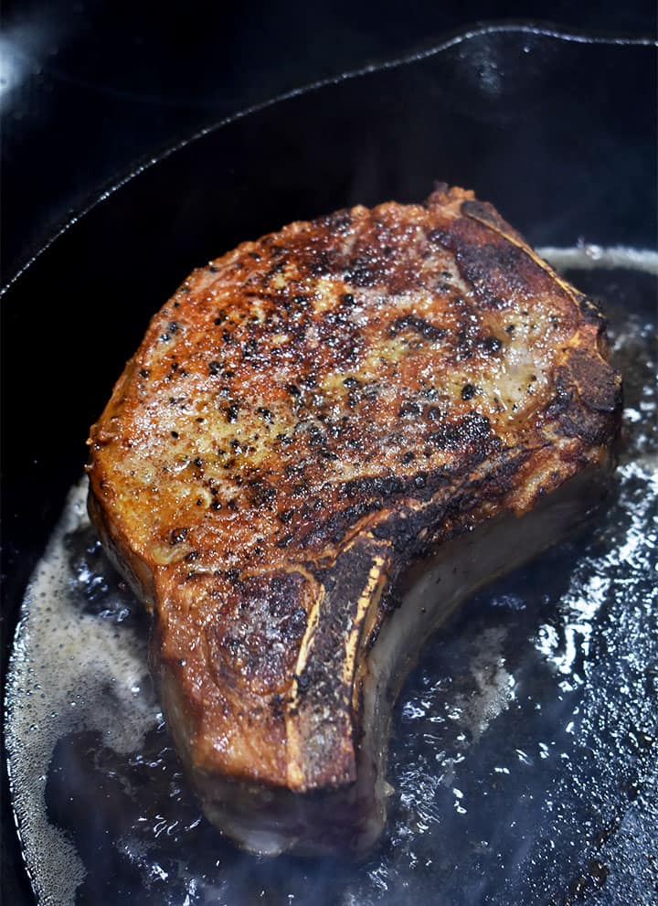 sous vide pork chop searing in a cast iron pan
