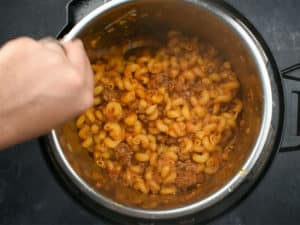hand stirring cooked goulash in an instant pot
