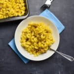 mac and cheese in a white bowl with a blue napkin on a gray table